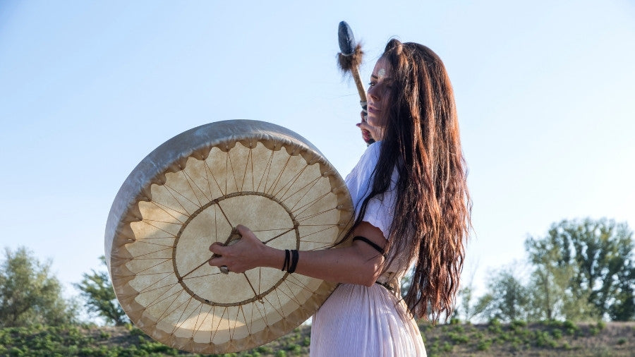 Woman holding up a shamanic drum and rattle