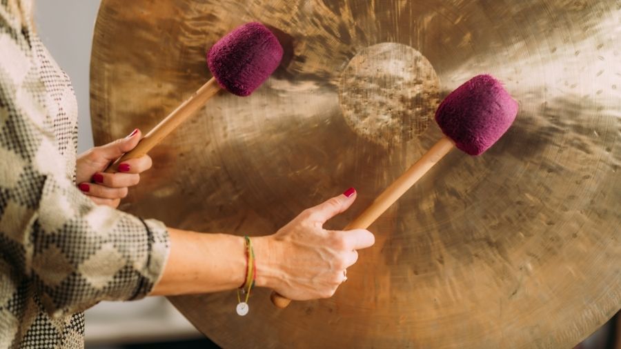 Sound bath therapy session with a person playing a gong