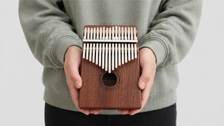 A girl holding and playing a kalimba with both hands.