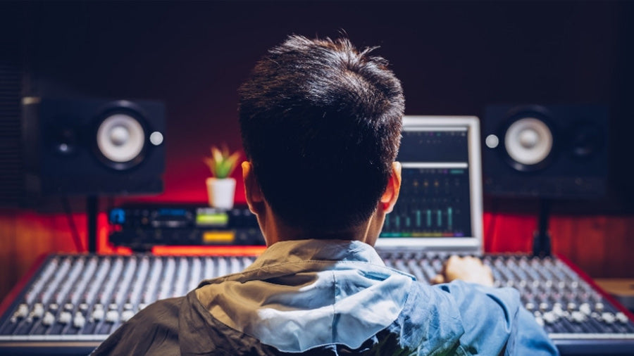 Man in music studio with mixing desk and DAW
