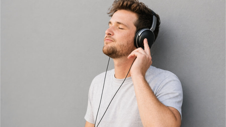 A calm man wearing headphones with gray studio background