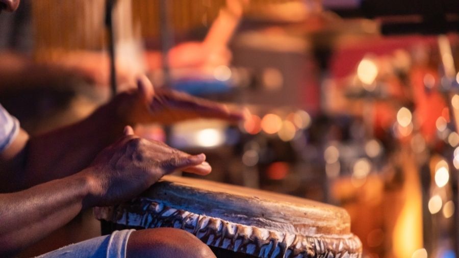 A person playing an African djembe drum with their hands.