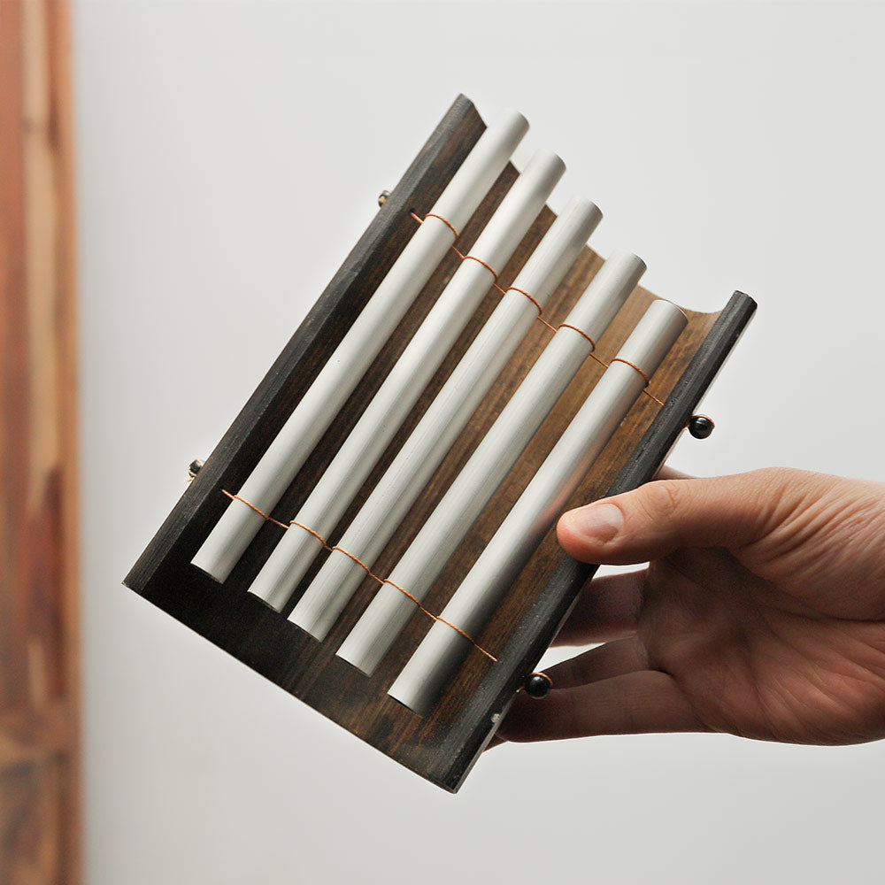 A Balinese Gamelan 5-note metallophone held in hand to demonstrate its size and portability.