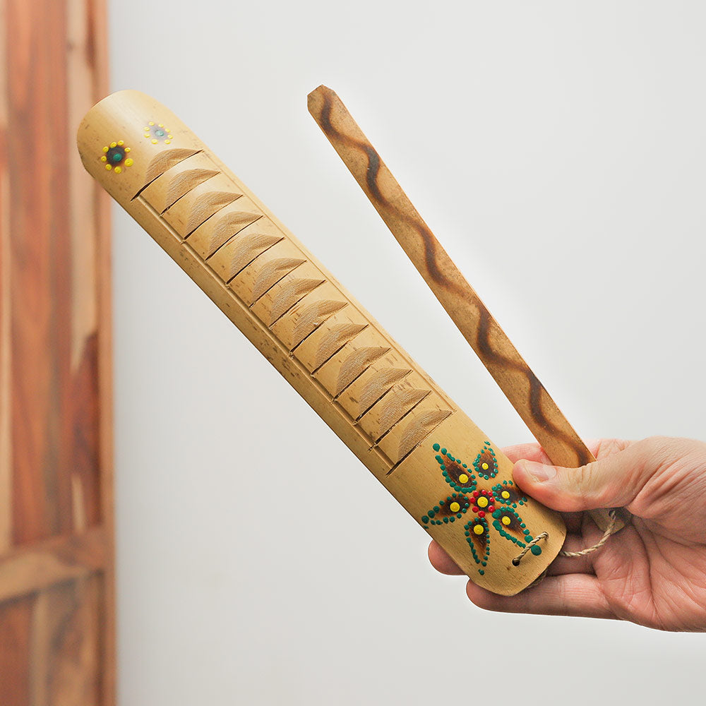 Bamboo Rumbai guiro and wooden scraper held in hand to show scale and size.