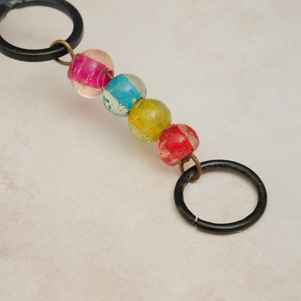 Close up of the round hanging loop of the cast iron windchime with colourful glass beads for decoration.