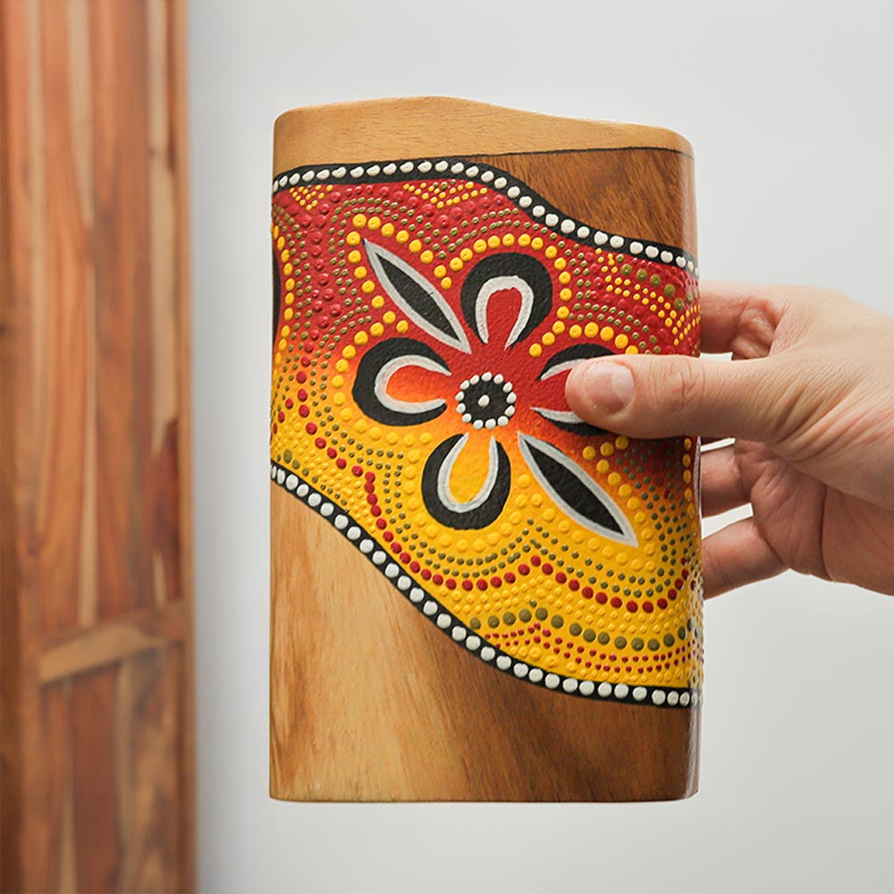 Close-up of a colorful hand-painted pocket didgeridoo, held in hand to show scale.