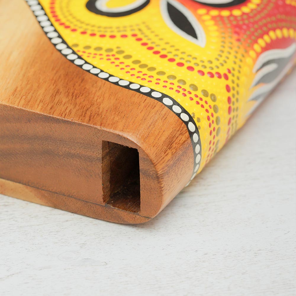 Close-up of the sound opening of a wooden hand-painted didgeridoo, highlighting the craftsmanship and detail where the sound escapes.