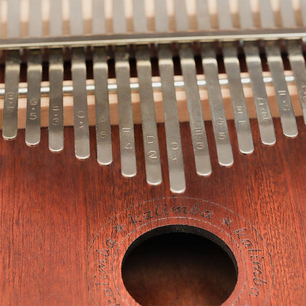 Close-up of the metal key tines on the Yulin Wooden Kalimba 17-note, showing the letter and number notes engraved for tuning.
