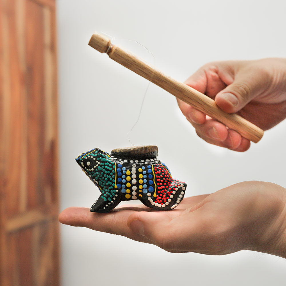 Croaking frog sound effect instrument held in hand, showcasing its size and design.