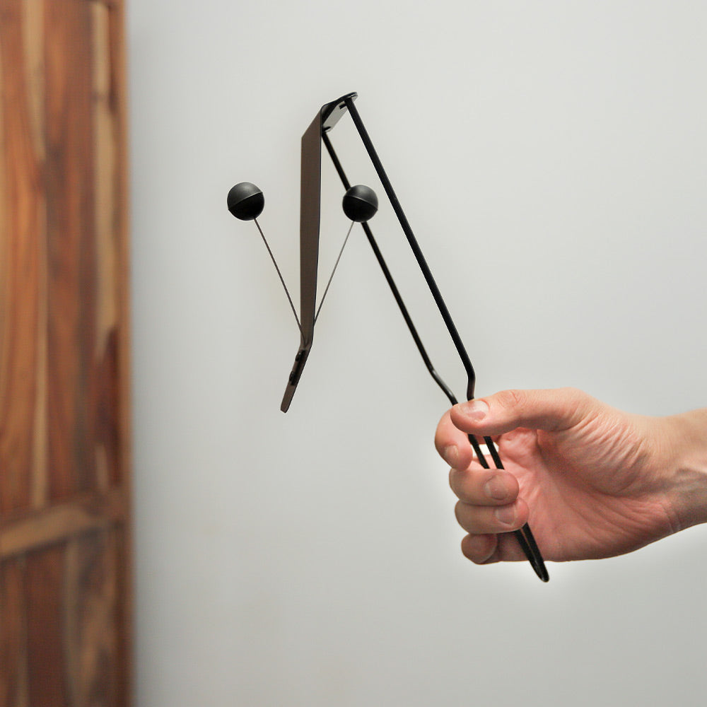 Flexatone instrument held in hand, showing its size and metal construction.