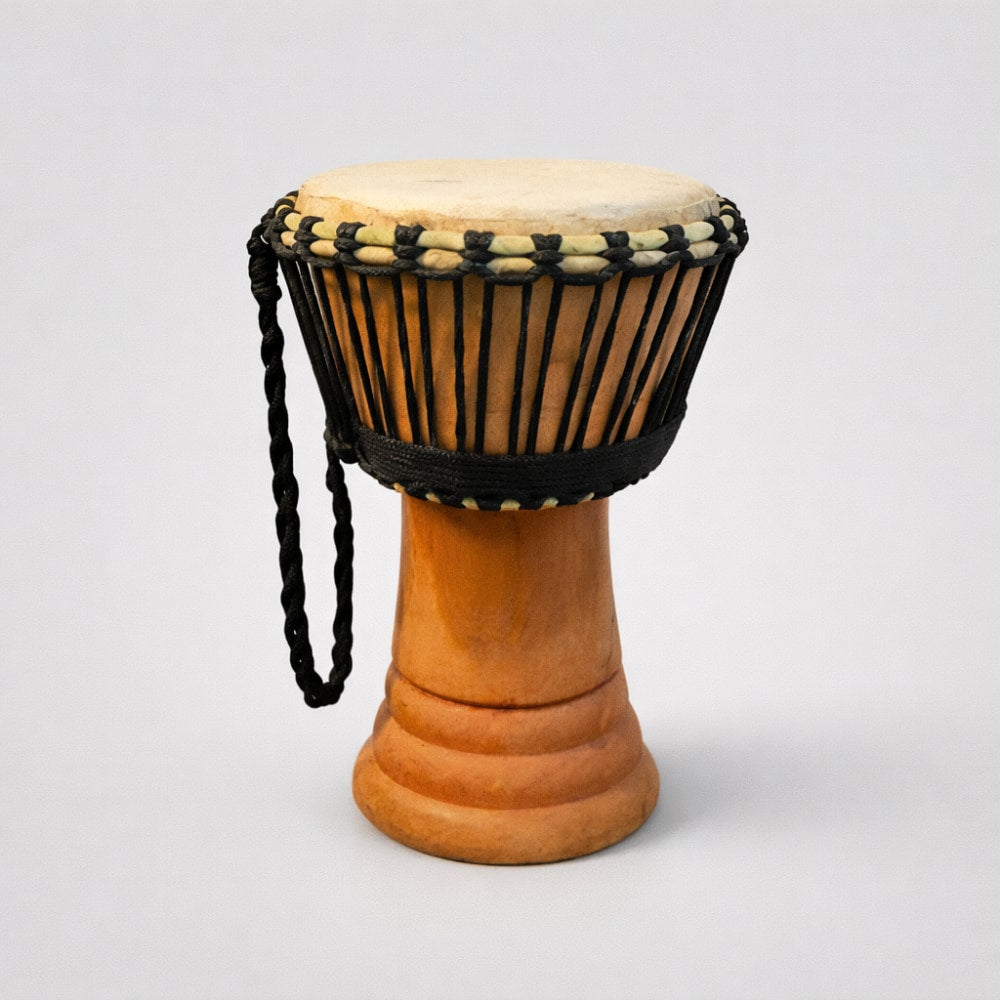 Small Rope-Tied African Wooden Djembe Drum from Ghana with a black rope around it on a light gray studio background