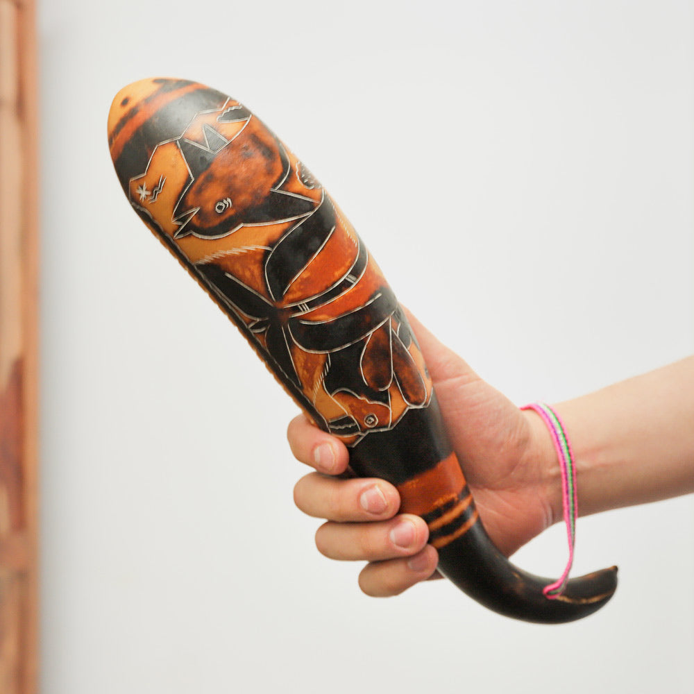 Gourd Guiro shaker held in hand to show scale, highlighting its natural texture and handheld design.