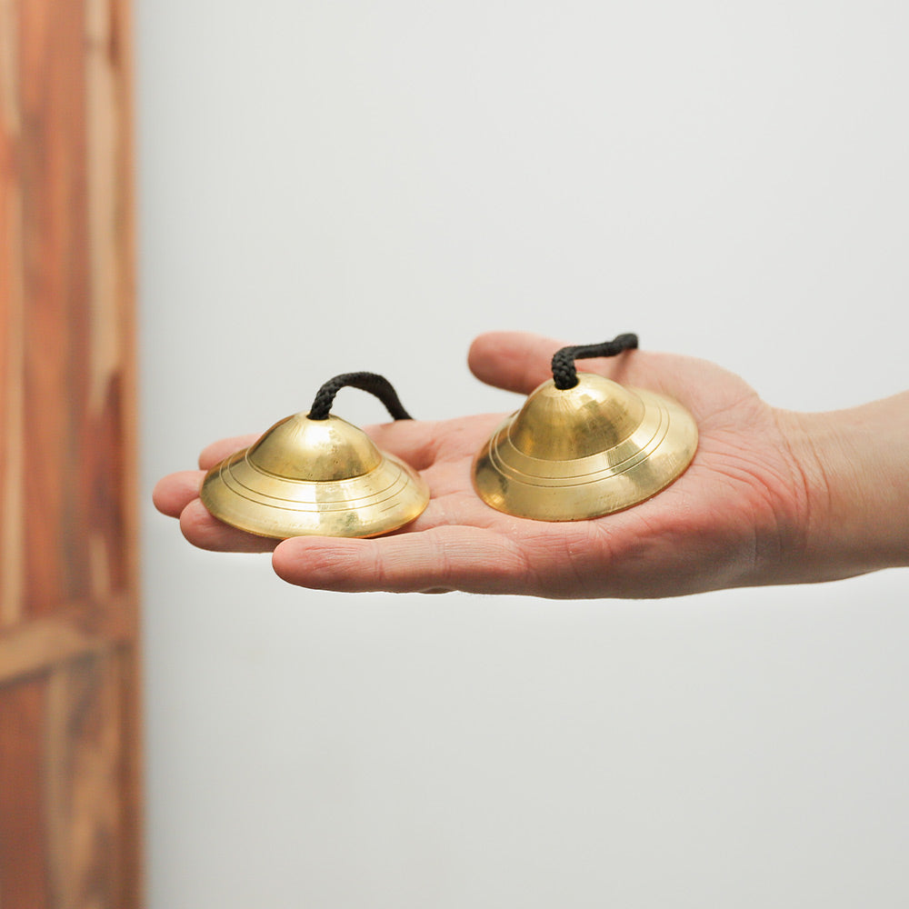 Indian Manjira bells held in hand, showing their size and detailed design without the rope.