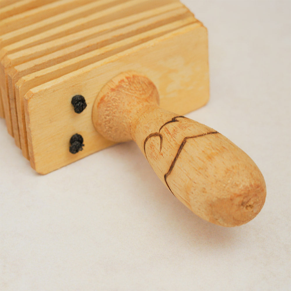 Close-up of the Indonesian wooden kokoriko handle, showcasing its detailed texture.