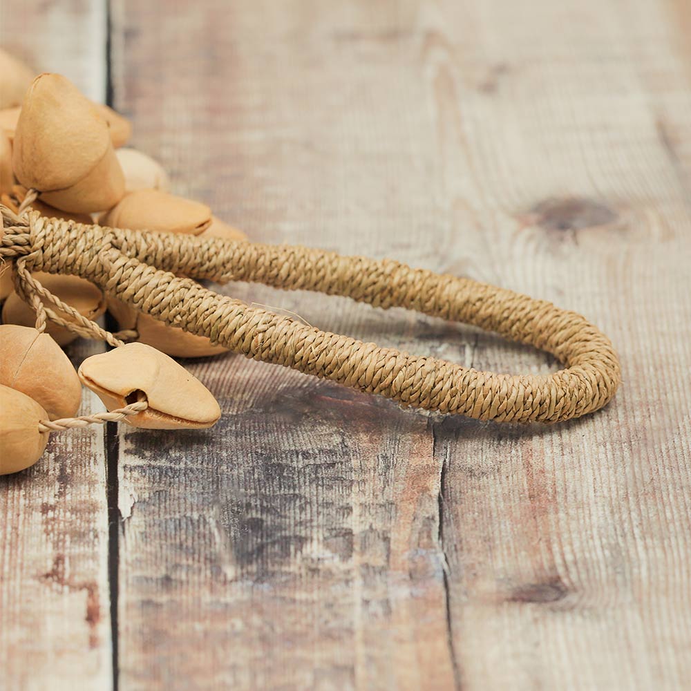 Close-up of the Lima nut cluster sound therapy instrument showing natural kenari seeds and a wide loop for holding or hanging.