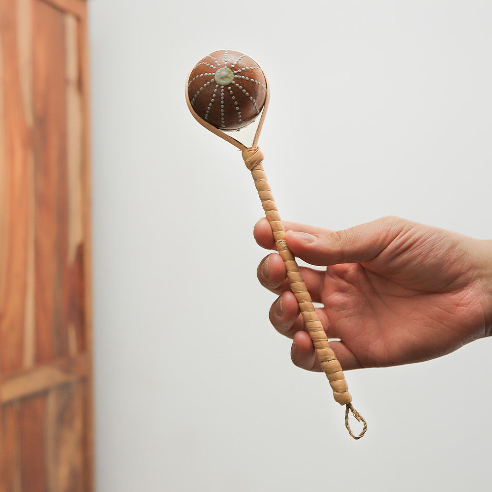 Close-up of painted rattan Sawan shaker held in hand to show scale and size.
