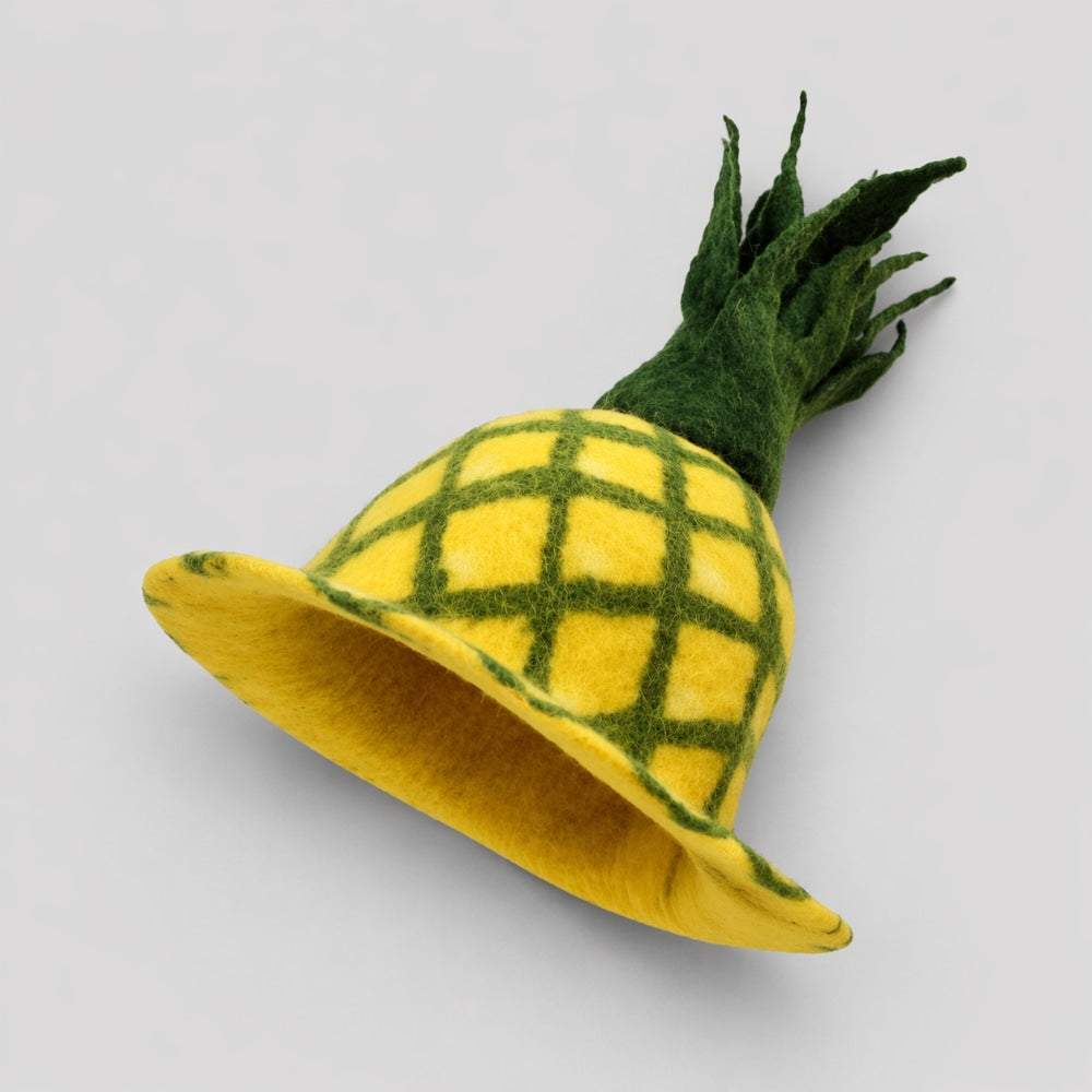 Yellow and green pineapple shaped felt fruit haton a light gray studio background