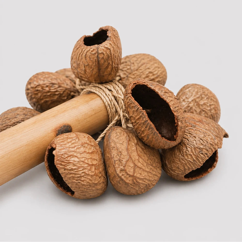 Close up of the Raha stick shaker showing the bamboo handle and large natural seeds tied to the handle.