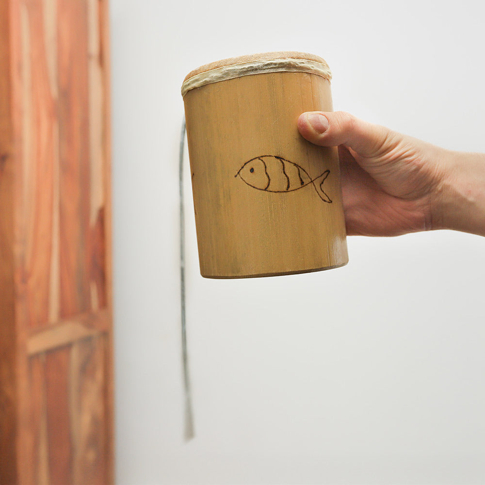 Thick bamboo Jati thunder drum held in hand, demonstrating its size and design.