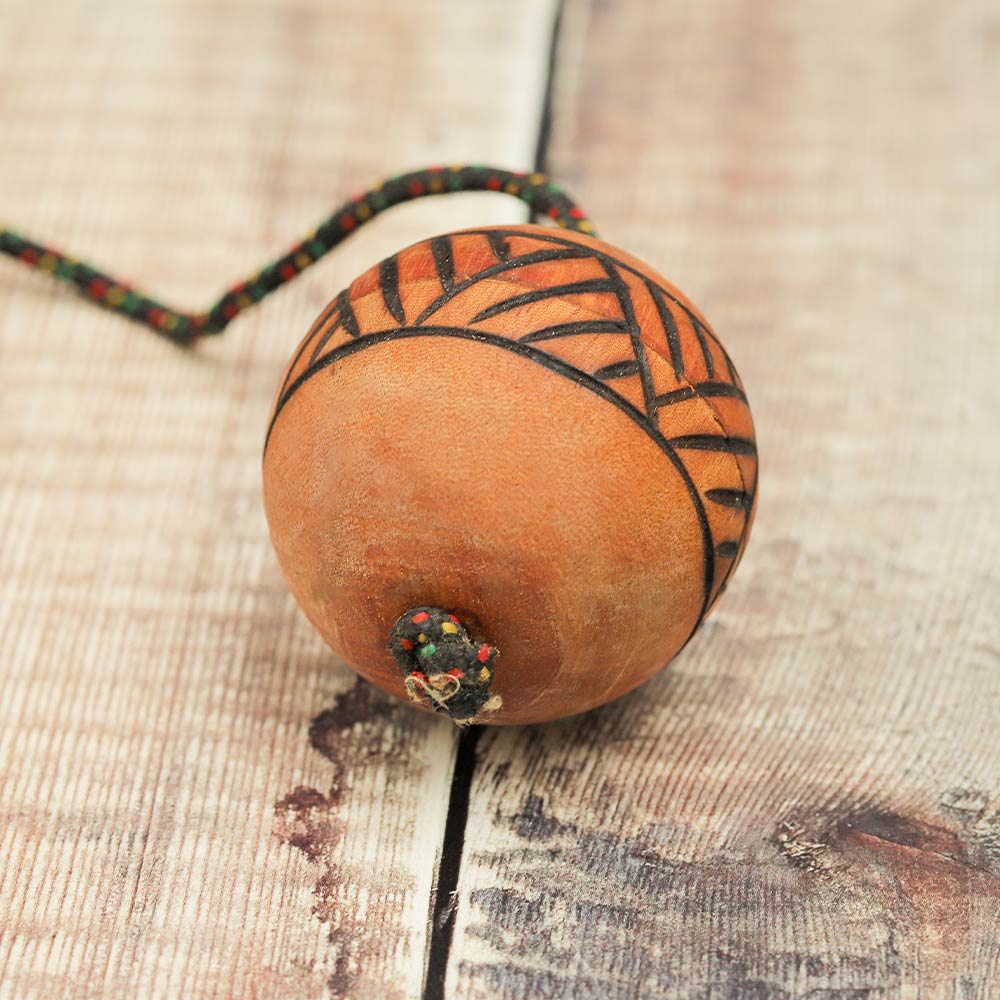 Underside of the wooden Kashaka shaker showing how the rope is inserted into the cas ball.