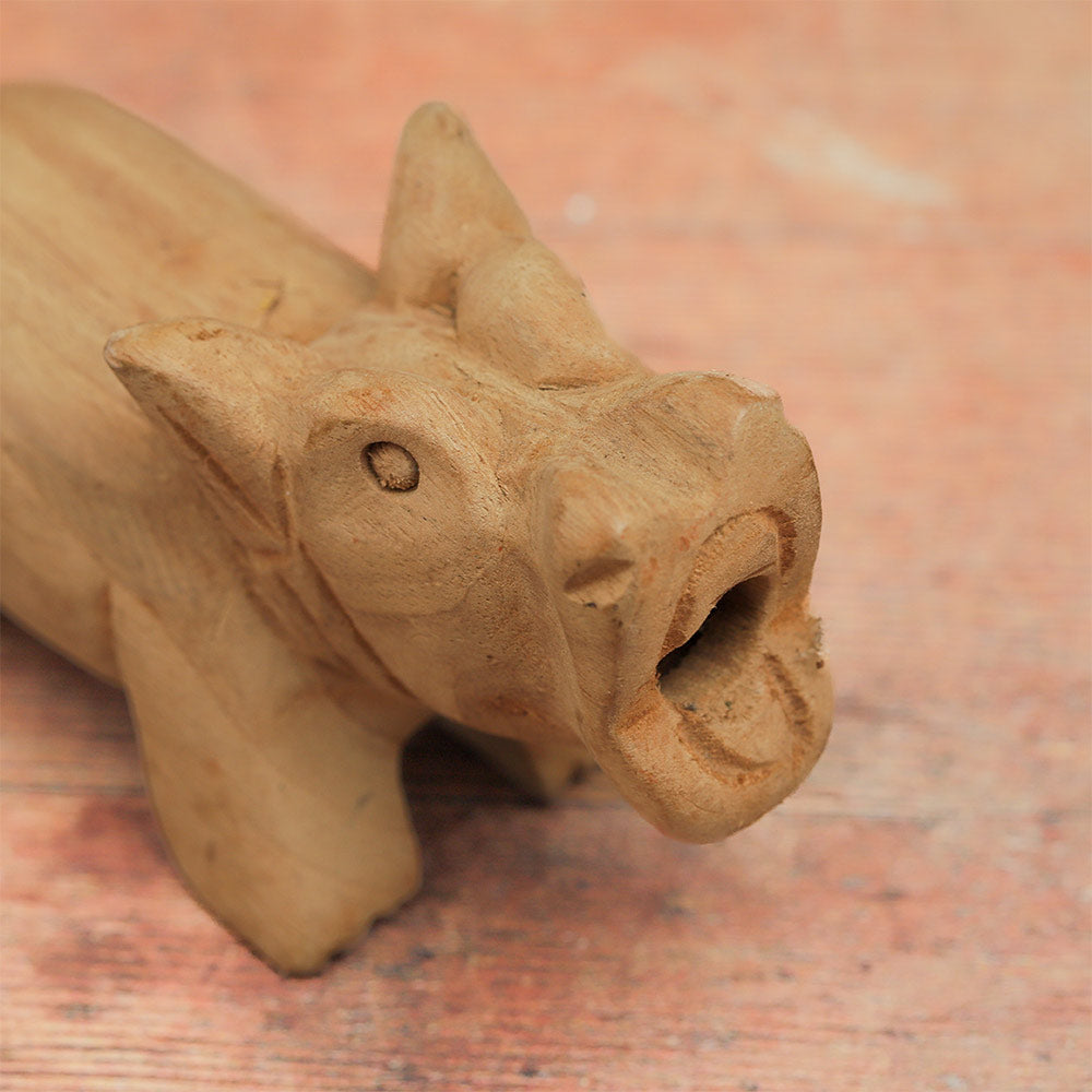Close-up of the wooden pig whistle's face, highlighting its carved features and expression.