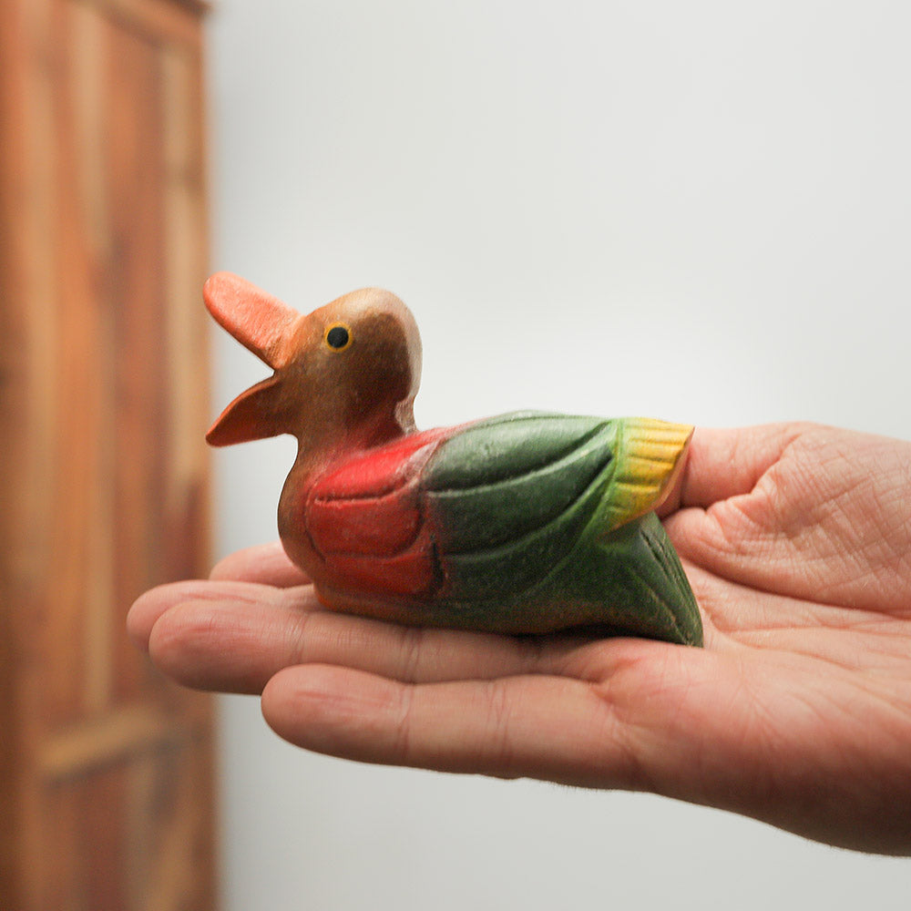 Wooden sitting duck whistle held in hand to show its size, highlighting its carved details and natural wood finish.