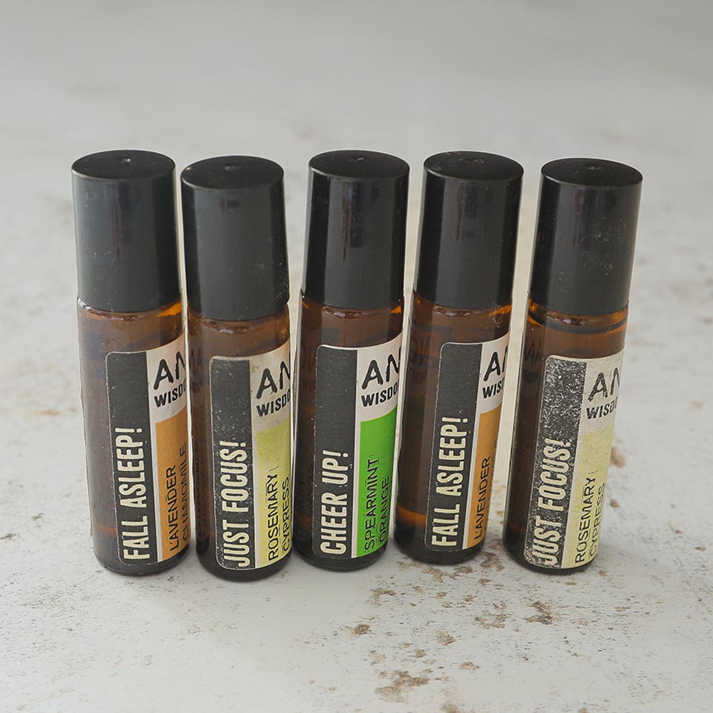 5-piece Essential Oil Rollerball Blends Set featuring various blends including Just Focus, Fall Asleep, and Cheer Up, in sleek glass bottles with rollerball applicators