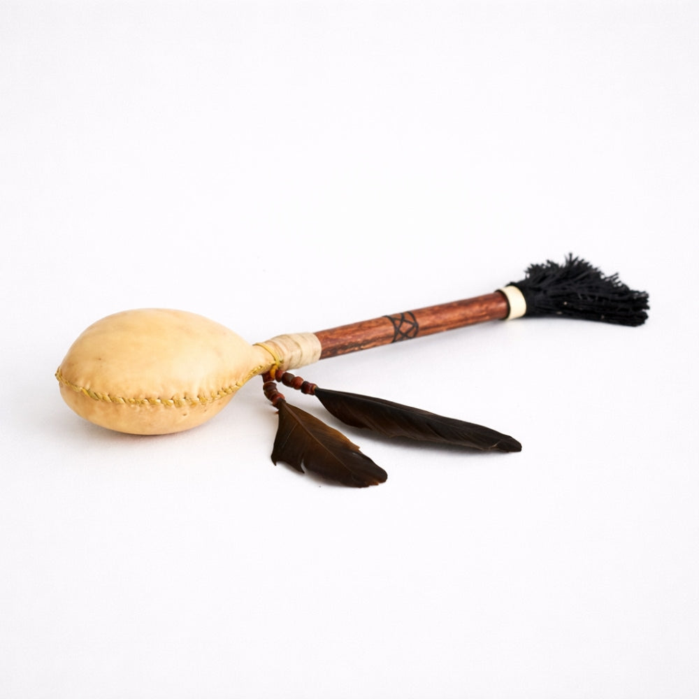 Wooden Terre shamanic rattle shaker with animal hide and feathers on a white studio background