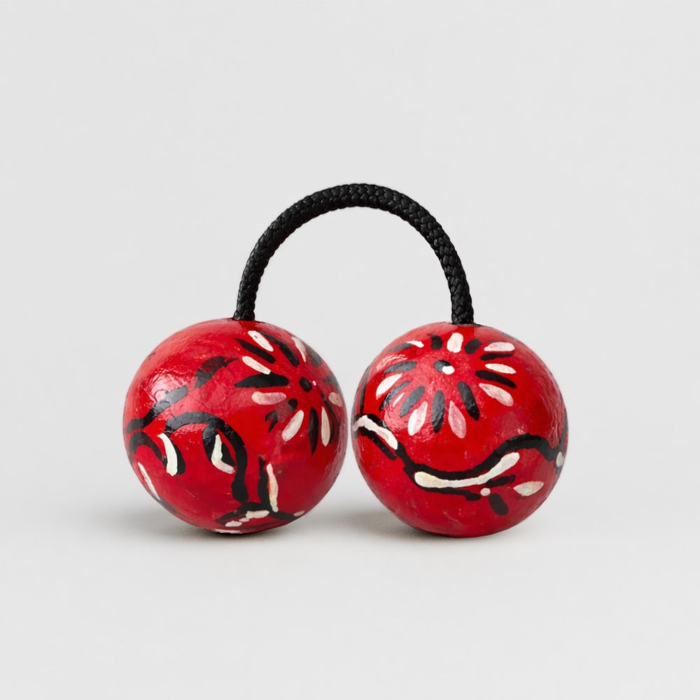 Tribal painted african kashaka shaker with black and white designs on a light gray studio background