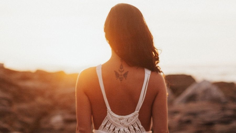 A confident woman standing tall, gazing towards the sea, embodying strength and self-assurance.