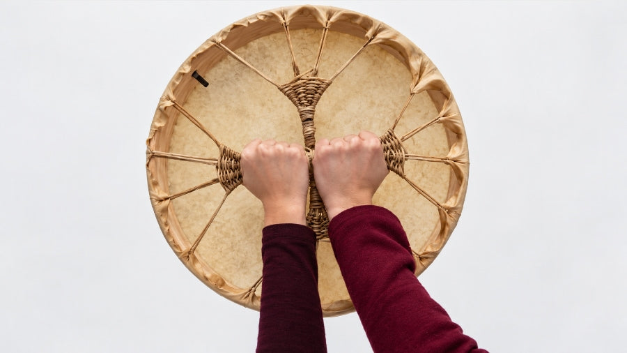 Cows hide shamanic drum with two hands holding the grip