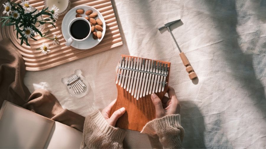 A woman holding a kalimba in a cozy, relaxing atmosphere, with a cup of coffe