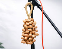 Lima nut cluster shaker made from natural seeds, hanging on a microphone stand in a clean studio setting, showing an organic percussion instrument used for rhythm and sound therapy.