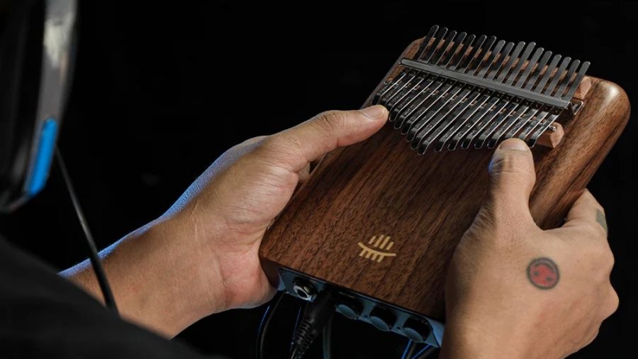 A man holding an EQ Black Walnut kalimba with 21/17 keys, prepared for recording.