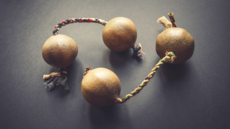 Traditional African Kashaka Shaker instrument on a grey background.