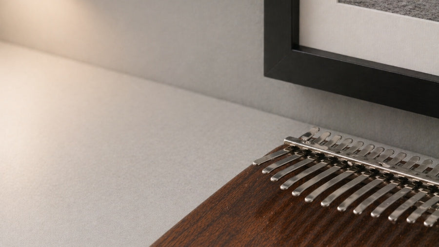 Close up of wooden board kalimba with oxford photo frame in background with soft warm lighting in apartment.