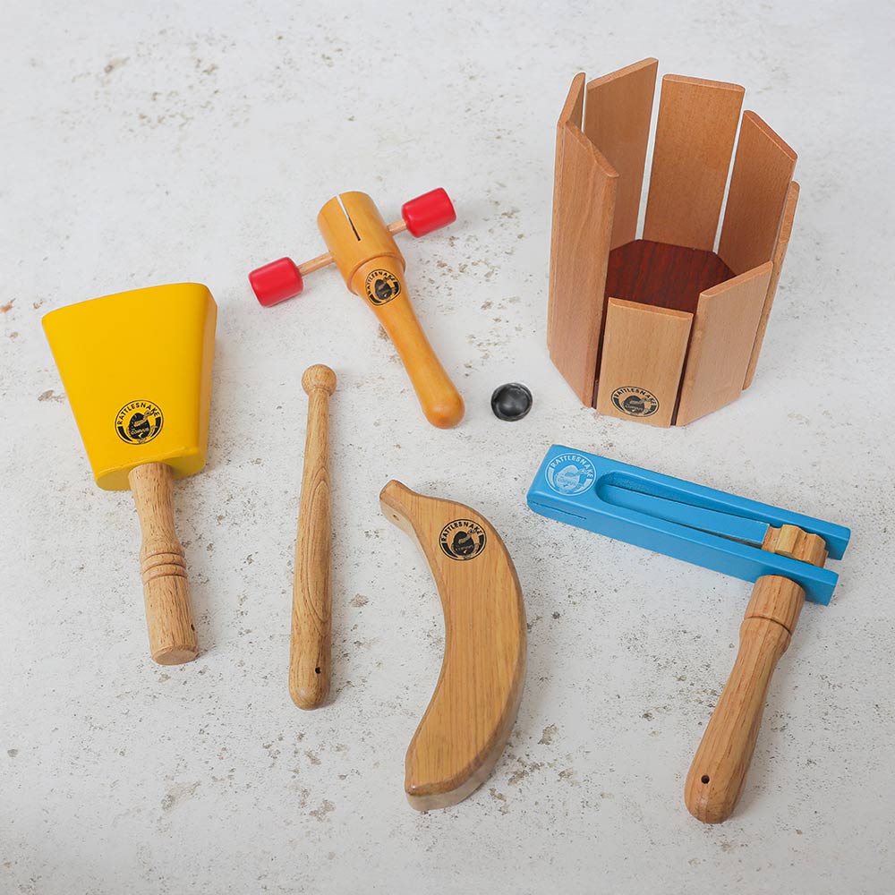 Bundle of rattlesnake percussion instruments including yellow cowbell with beater, t shaker, banana shaker, blue football ratchet  and xylophone standing with marble