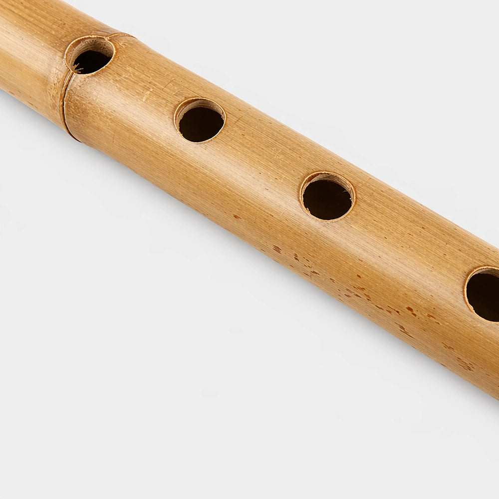 Close-up of a wooden flute with four holes on a light gray background