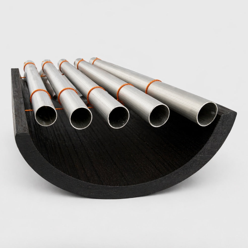 Close up of a gamelan instruments set of metal notes with black and orange bands on a white studio background
