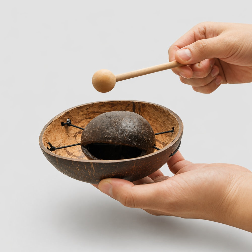 Coconut husk tone block percussion instrument with beater held in hand to show its size and scale.