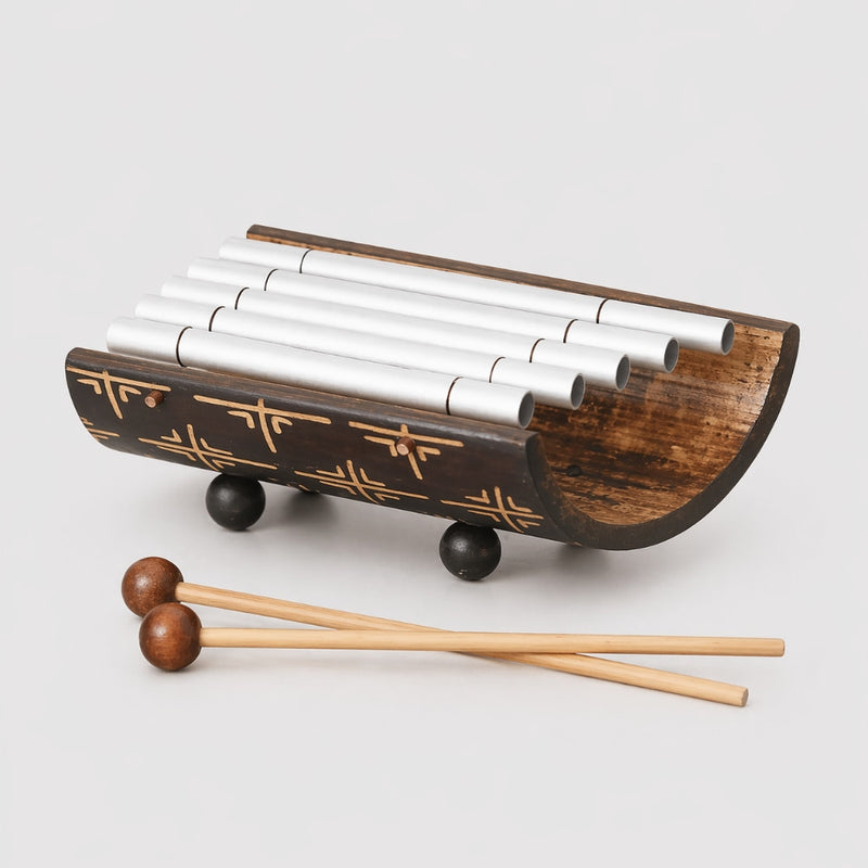 Wooden xylophone with metal bars and wooden mallets on a light gray background