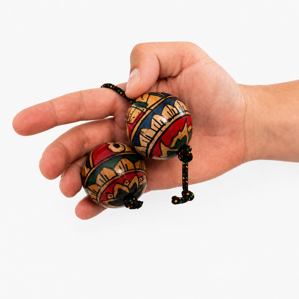 Hand holding geometric kashaka shaker with a white studio background