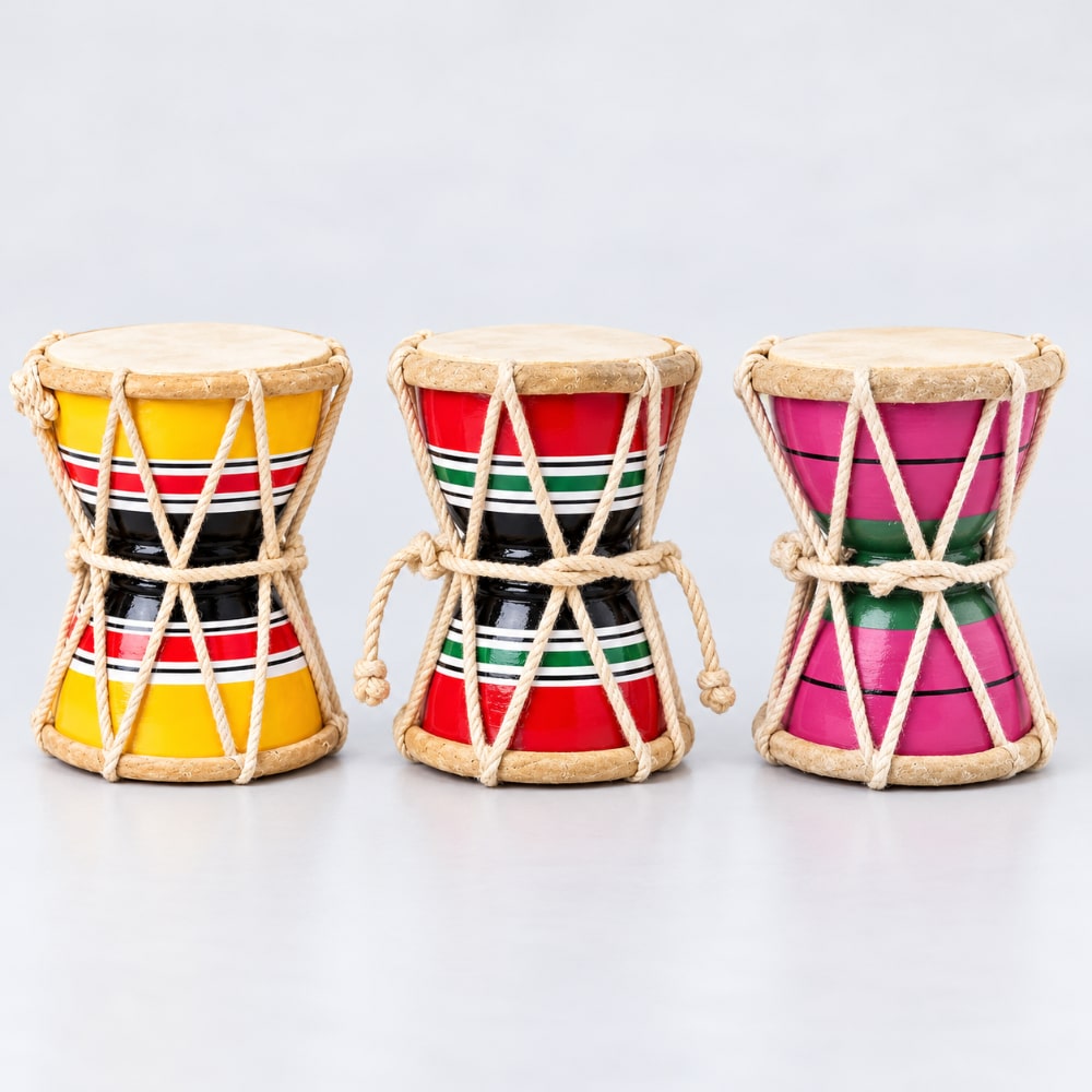 Three small indian damaru hand drum designs with natural rope wrap and drumheads on a light gray background.