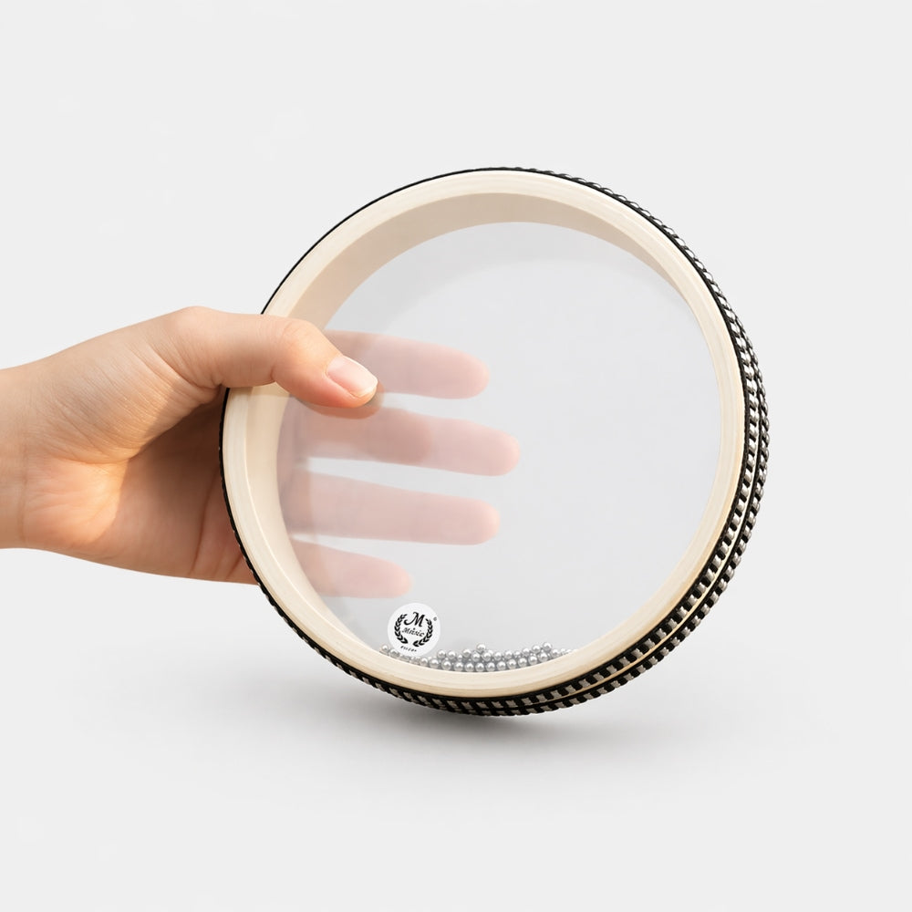 Hand holding a small round 6" ocean drum with black and white ribbon on the edge with a white studio background