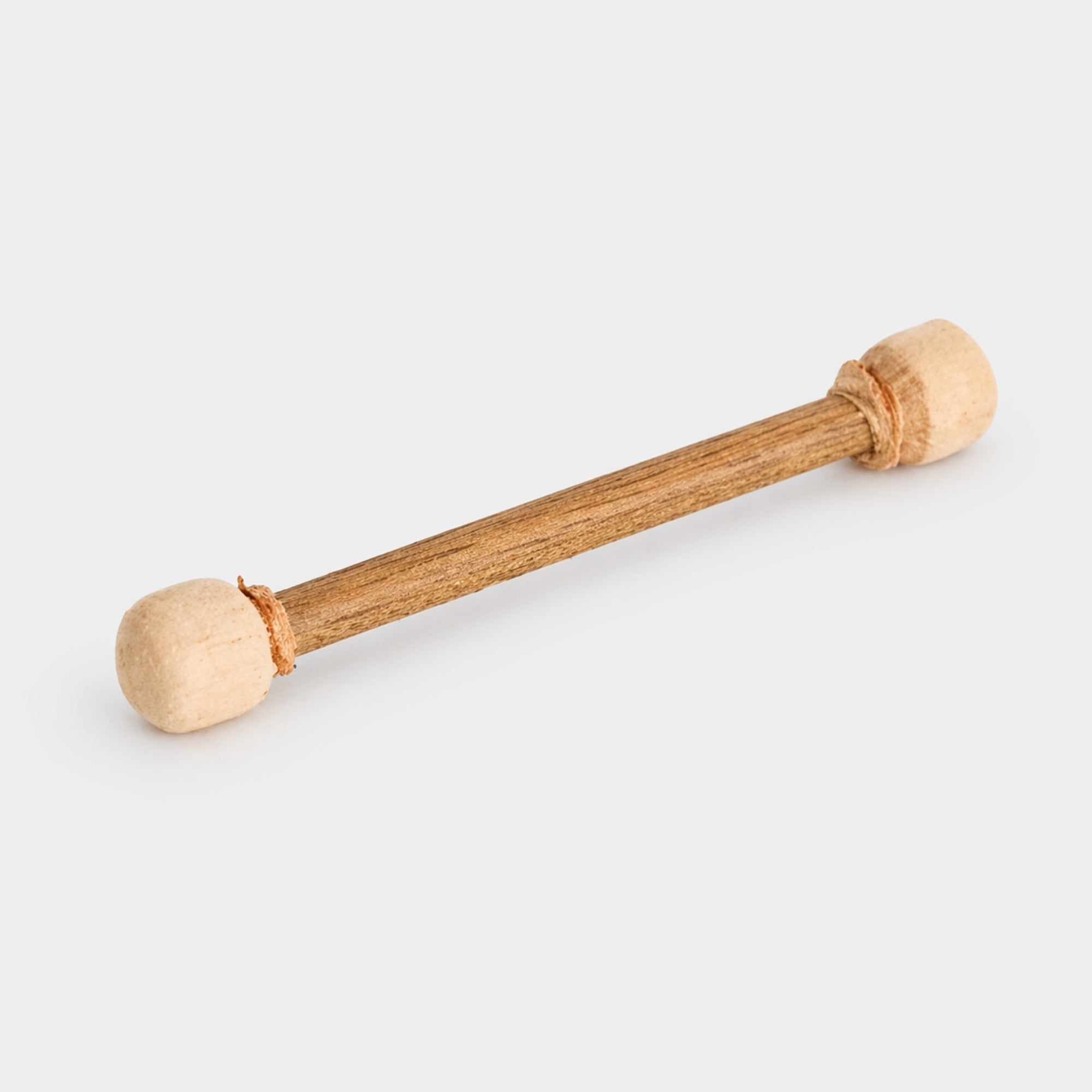 Double sided wooden drum beater with suede ends on a light gray studio background