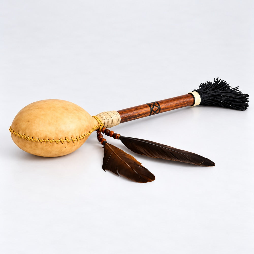 Wooden Terre shamanic rattle shaker with animal hide and feathers on a white studio background